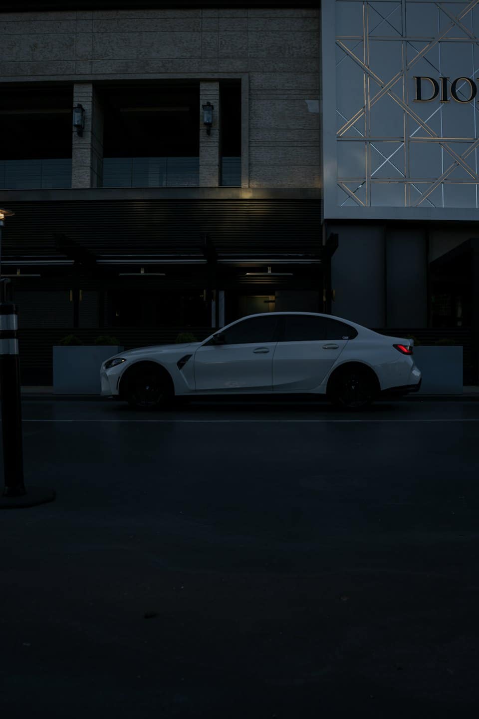 Valge luksuslik sportauto pargitud linnatänavale hämaruses.